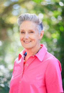 portrait of Kim Bedier, CVE, in vibrant pink shirt, in front of green landscape