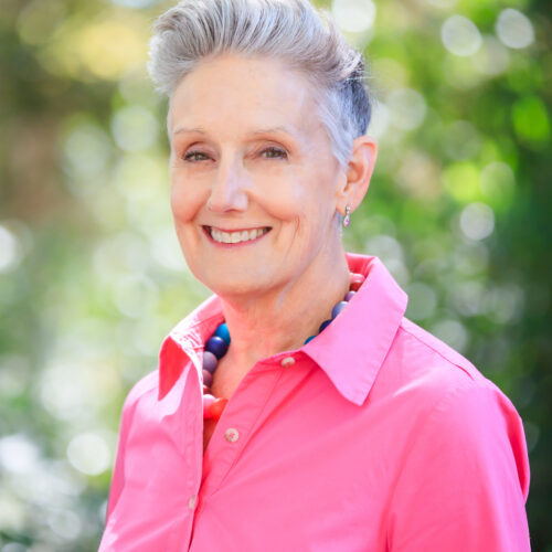 portrait of Kim Bedier, CVE, in vibrant pink shirt, in front of green landscape