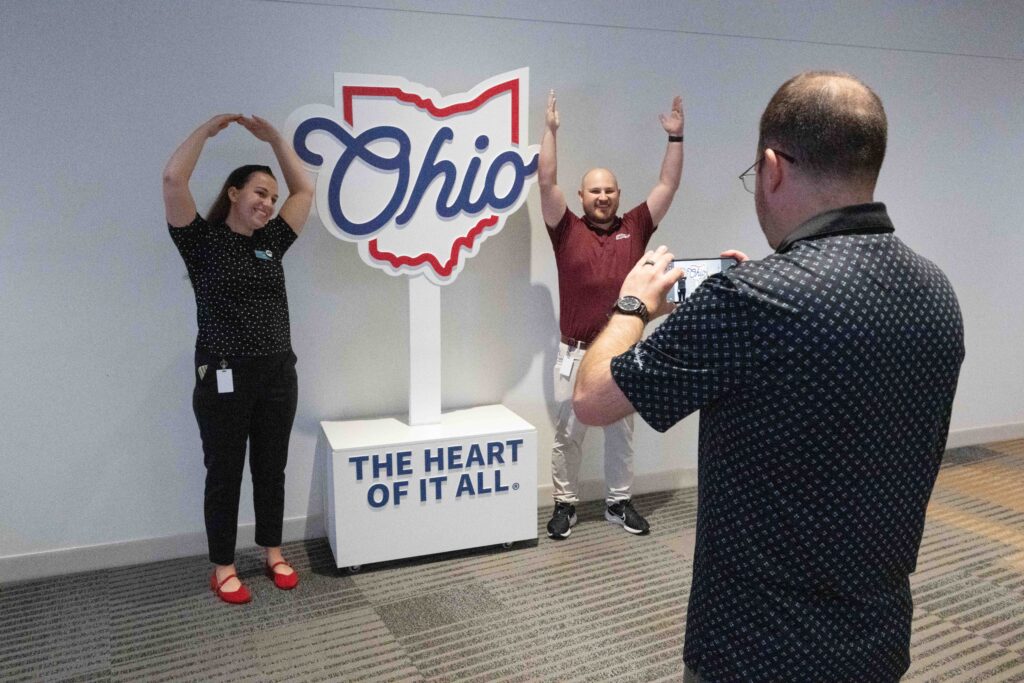 two people pose for a photo opportunity by a sign that says "Ohio. The heart of it all."