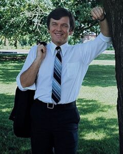 Robert Lister casually leans on tree, smiling