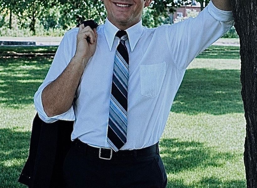 Robert Lister casually leans on tree, smiling
